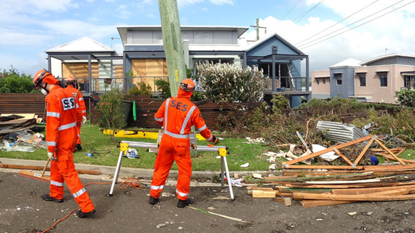 NSW SES members assess damage in front of a house after a storm.