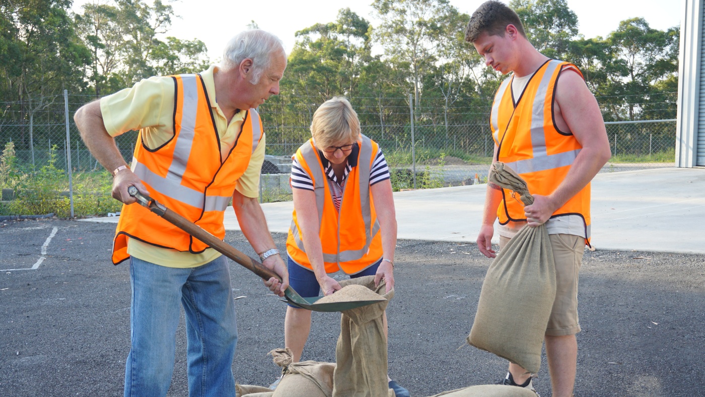 Three NSW SES community action team volunteers filling sandbags.